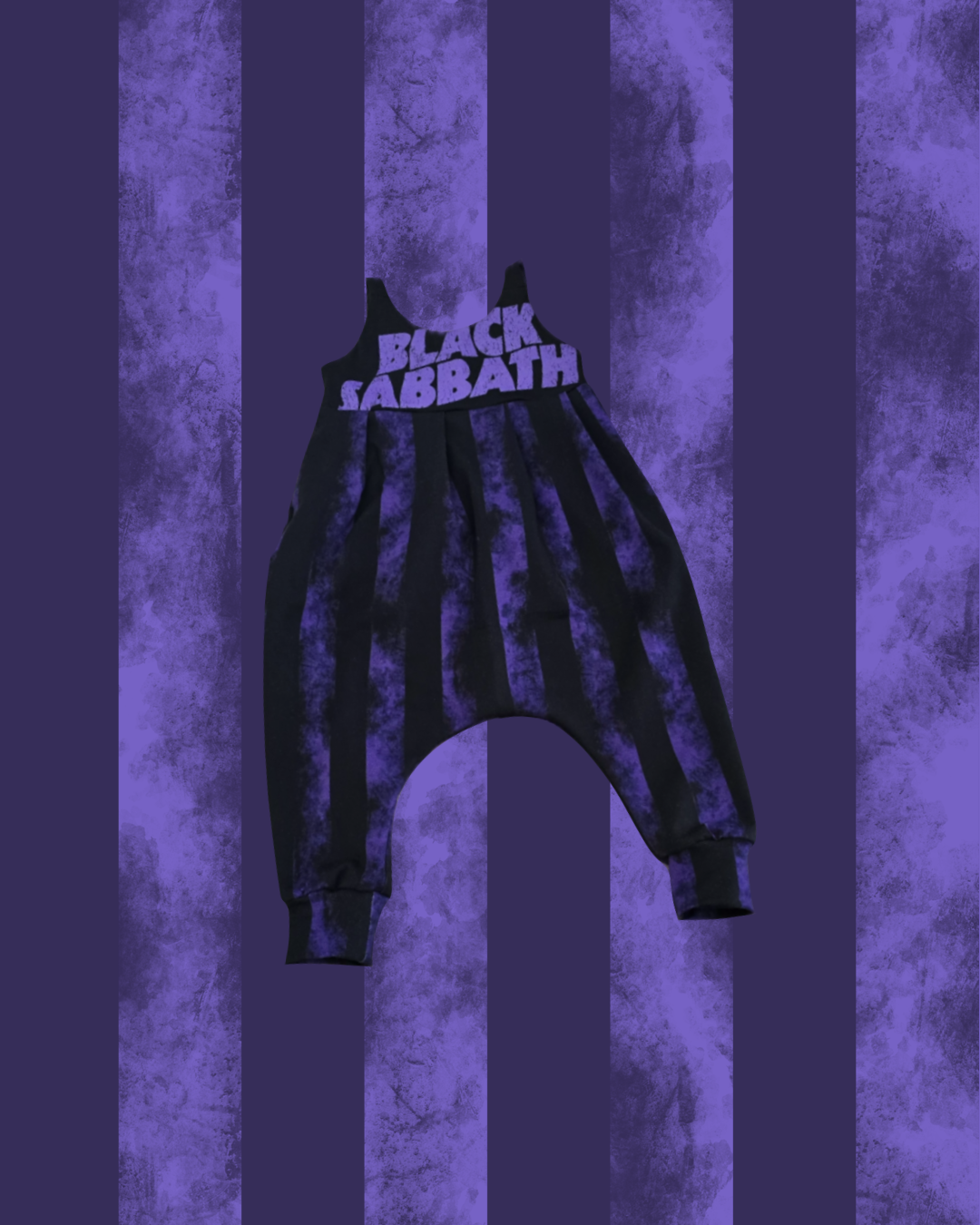 Black harem-style sweatpants with purple tie-dye vertical stripes and 'BLACK SABBATH' printed in white across the waistband, shown against a purple striped textured background.