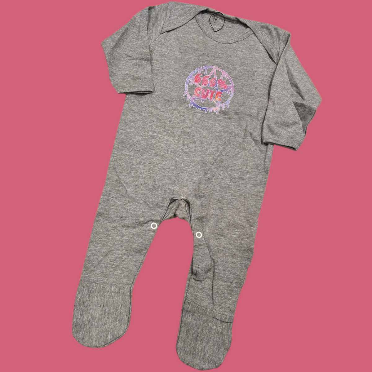 Gray baby onesie with a colorful 666% cute design design on a pink background