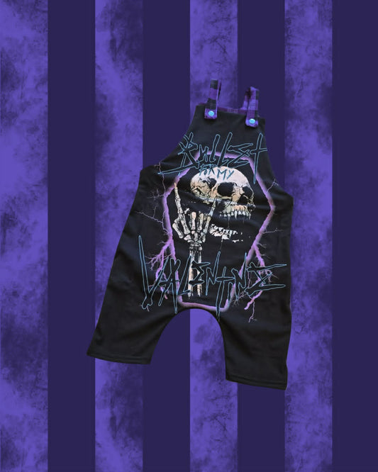 Black BULLET FOR MY VALENTINE dungarees with a large graphic print featuring a skull, skeleton hand, and stylized text, shown against a purple striped background.