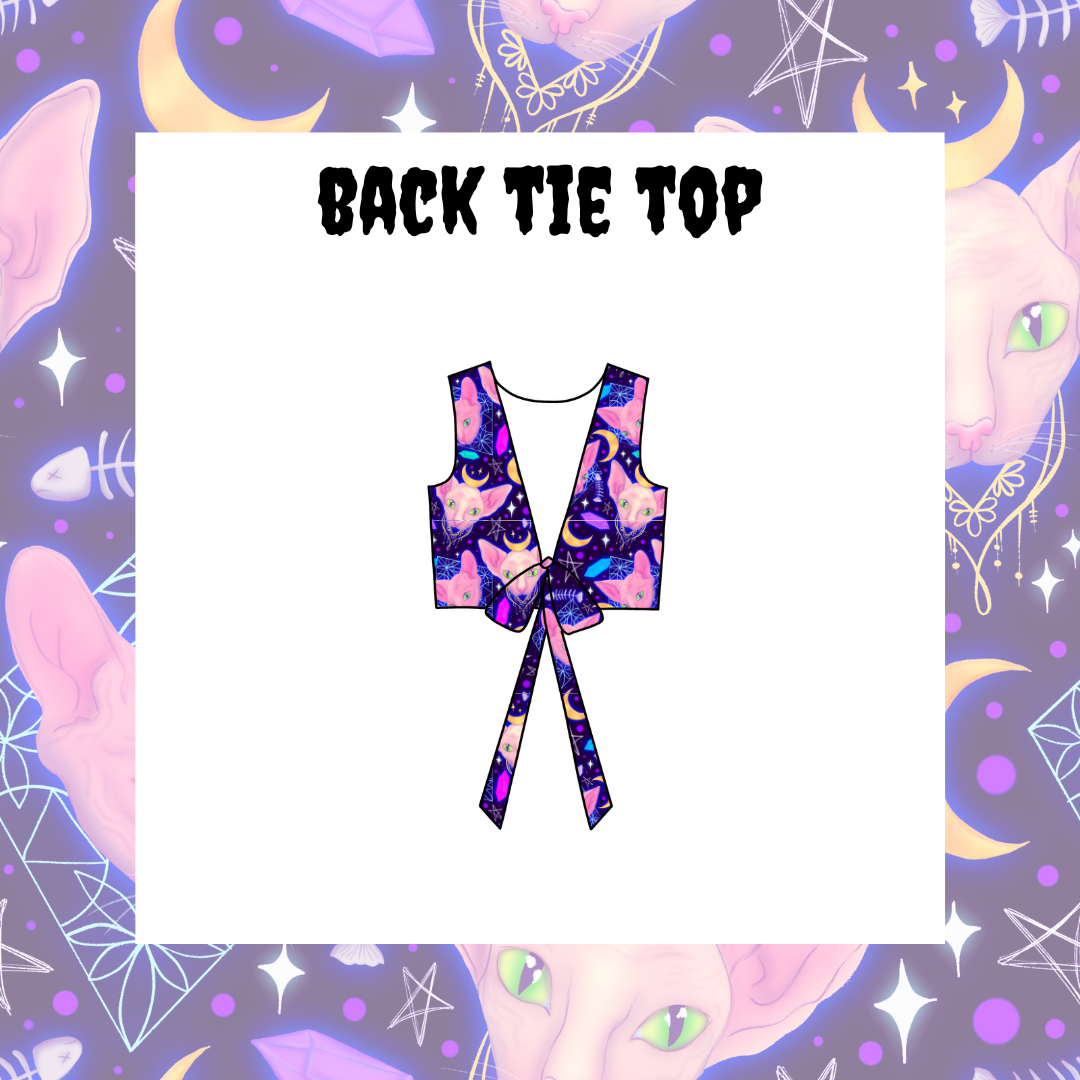 A back tie top featuring a multicolored tie-dye pattern on a purple background, displayed on a model with a fantasy-themed backdrop decorated with moons and stars.