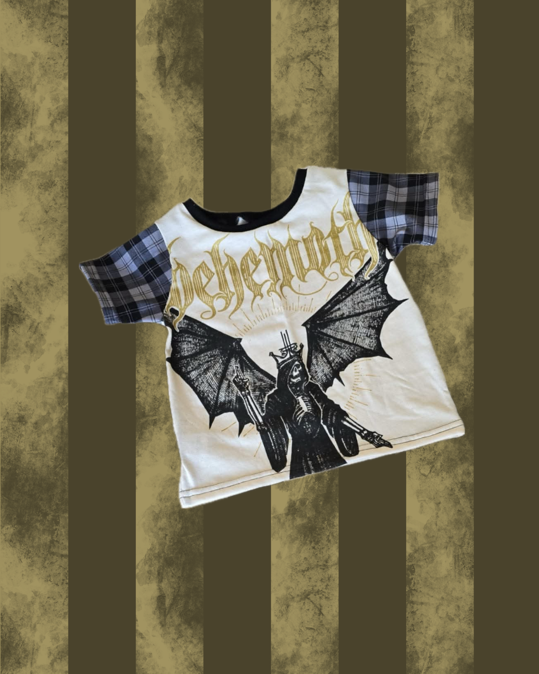 Cream BEHEMOTH tshirt with black bat design and plaid sleeves on a textured brown background