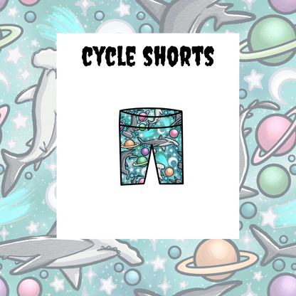 A graphic representation of kids' cycle shorts with a space and sea life theme, including planets, stars, and a shark.