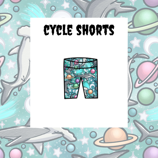 A graphic representation of kids' cycle shorts with a space and sea life theme, including planets, stars, and a shark.
