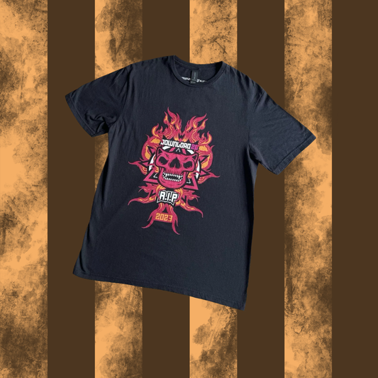 A black crew neck t-shirt with a graphic print of a flaming skull on the front, laid flat on a striped background.