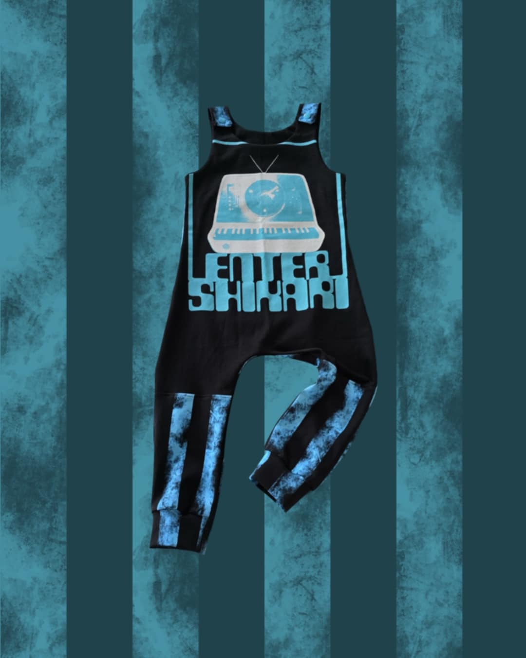 Black ENTER SHIKARI romper with blue and white design on a textured blue background