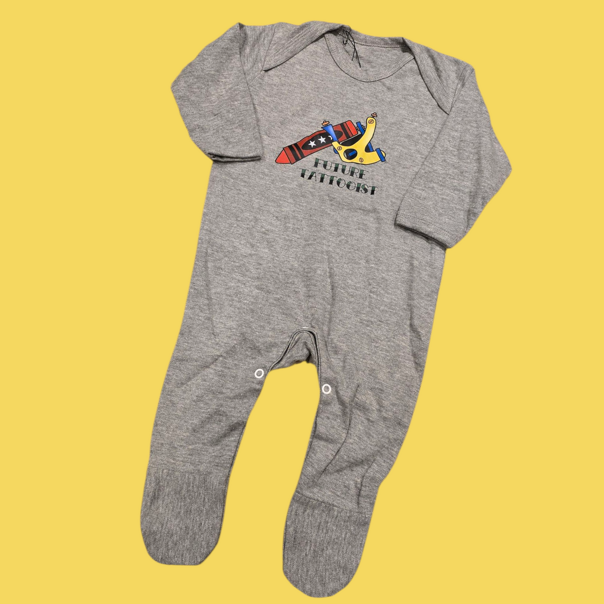 Gray baby onesie with colorful  Future Tattooist graphic and text on a yellow background