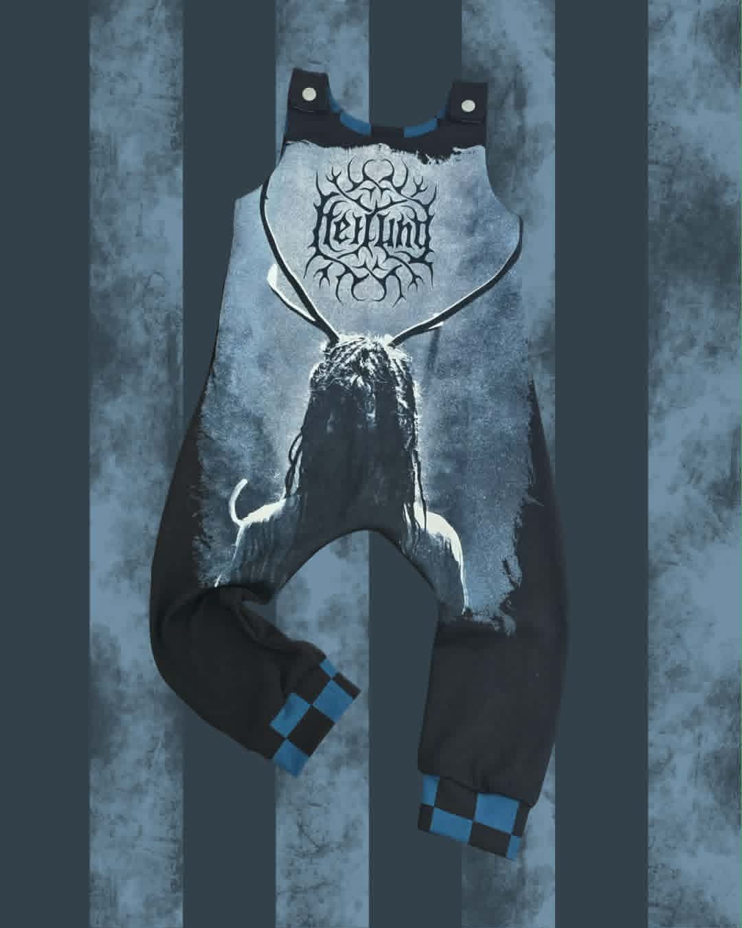 A black and blue graphic jumpsuit featuring a large white and blue skull graphic on the front with the word 'Heilung' in a gothic font, set against a dark blue and gray striped background.