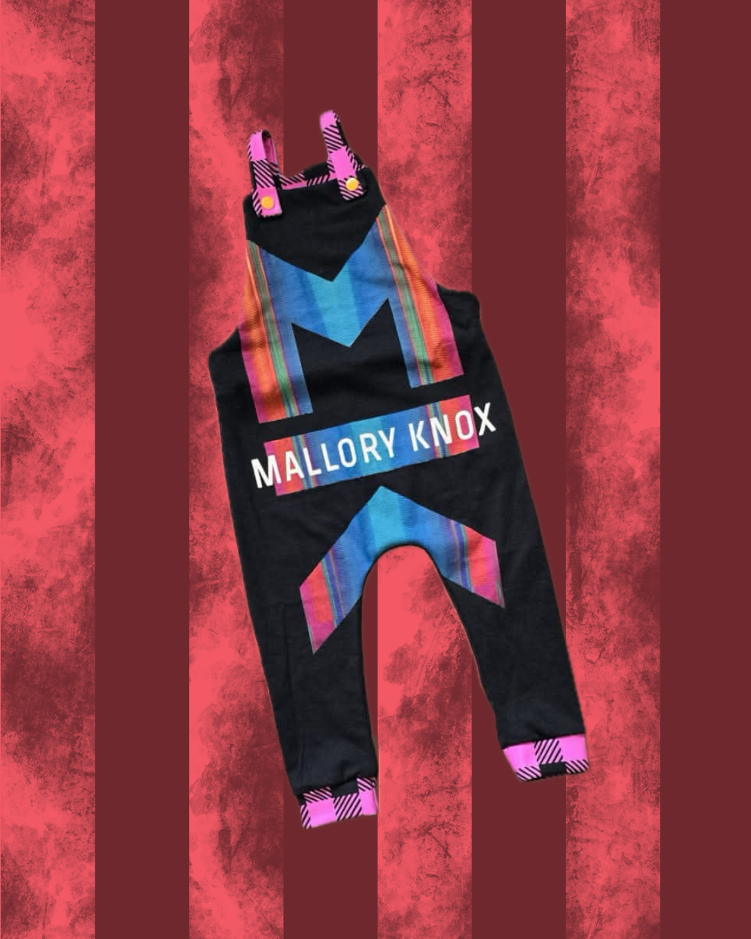 Colorful overalls with 'Mallory Knox' branding on a red striped background
