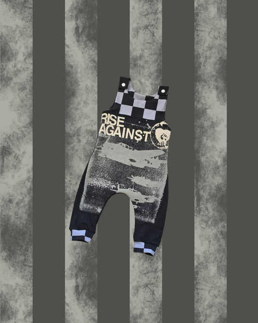 Dungarees with 'RISE AGAINST' text on a textured gray background