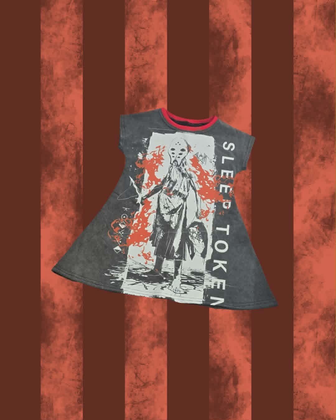 A short-sleeve gray graphic T-shirt dress with a horror-style print featuring a masked figure, red splatter details, and vertical white text reading 'SLEEP TOKEN', shown against a rust-colored striped background.