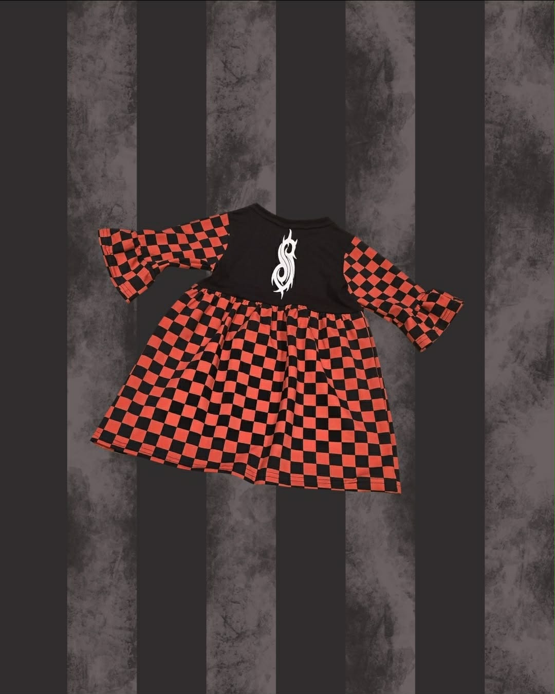 A toddler SLIPKNOT girl's dress featuring a black and red checkerboard pattern, with a solid black yoke and a white gothic dollar-sign graphic on the chest. The dress has three-quarter length flared bell sleeves.