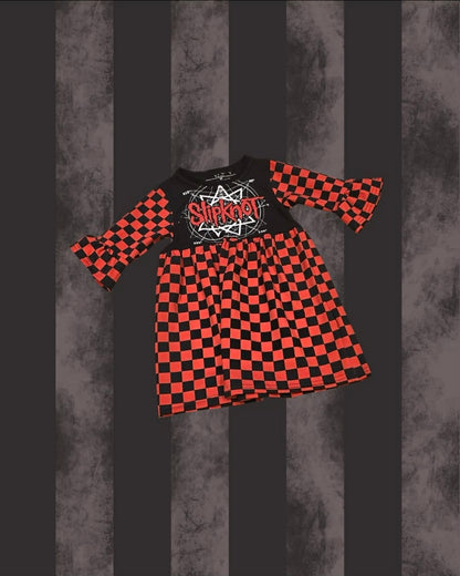A children's long-sleeve dress with a black and red checkerboard pattern, featuring a solid black chest panel with a white and red 'Slipknot' band graphic. The dress is displayed against a dark gray and black vertically striped background.