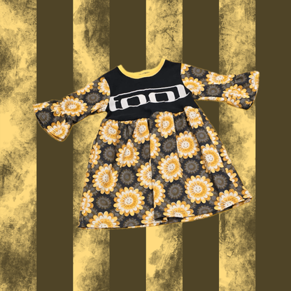 A black SMOCK with a floral pattern and the text 'TOOL' on the front, displayed against a striped background.