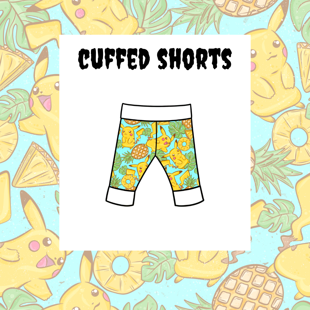 A pair of kids' cuffed shorts with a colorful character pattern and the text 'Cuffed Shorts' on the label.