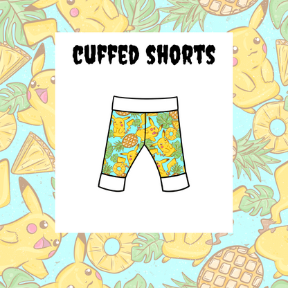 A pair of kids' cuffed shorts with a colorful character pattern and the text 'Cuffed Shorts' on the label.