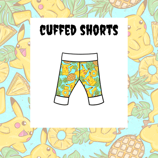 A pair of kids' cuffed shorts with a colorful character pattern and the text 'Cuffed Shorts' on the label.
